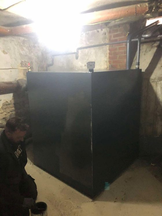 Citerne noire en cave avec un homme accroupi derrière