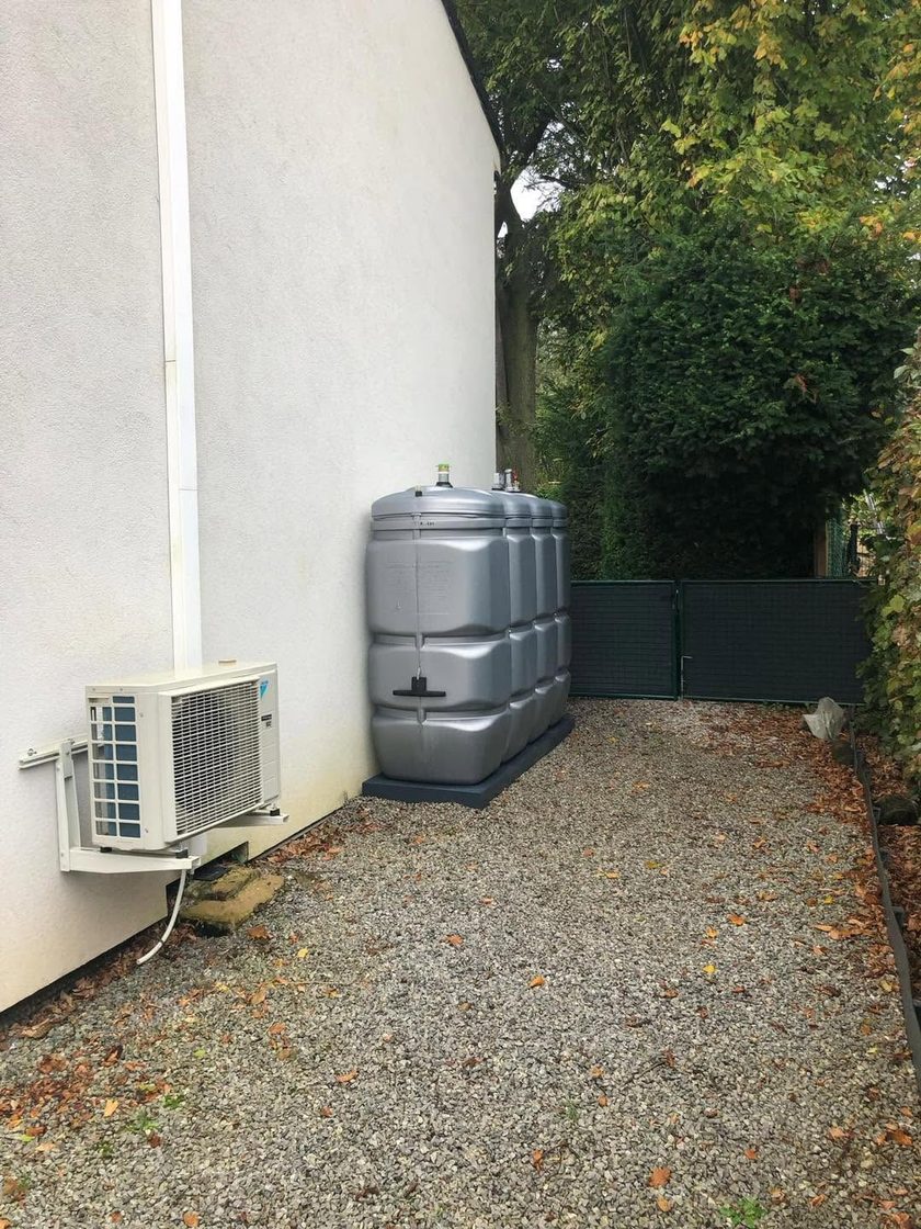 Module de citerne en polyéthylène gris posé sur gravier le long d'une façade