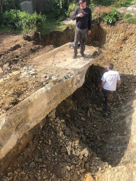 Tranchée profonde avec deux hommes au fond, terres excavées sur le bord