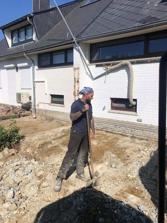 Ouvrier pelletant devant une maison blanche