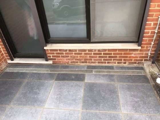Terrasse dallée avec caniveau devant une baie vitrée